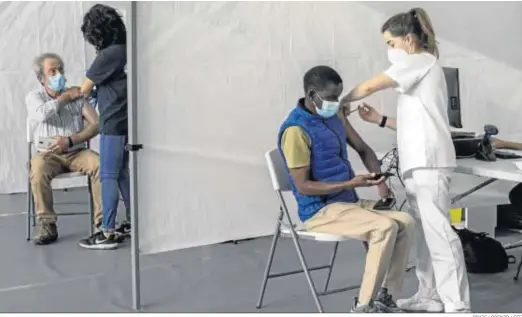 ?? BRAIS LORENZO / EFE ?? Dos personas reciben ayer la vacuna contra el coronaviru­s en el pabellón de deportes Paco Paz en Orense.