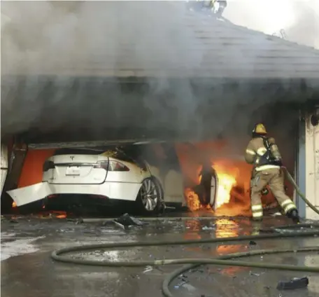  ?? AP FILE ?? BATTLING BURNING BATTERIES: An Orange County, Calif., firefighte­r works on extinguish­ing a burning Tesla in a garage. Federal authoritie­s say batteries in electric vehicles that catch fire pose special problems for first responders.