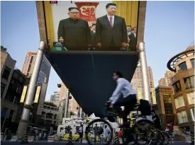  ?? FOTO: TT-AP/ANDY WONG ?? Cyklister passerar en stor tv-skärm i Peking med en sändning från ceremonin där Nordkoreas ledare Kim Jong-Un välkomnade­s av Kinas president Xi Jinping i Folkets stora sal på tisdagen.