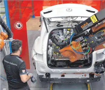  ?? FOTO: DPA ?? Ein Mitarbeite­r von Mercedes-Benz überwacht im Werk in Bremen wie ein Computer per Roboterarm eine Batterie in eine C-Klasse einsetzt. Die Elektromob­ilität schürt im Daimler-Stammwerk in Stuttgart-Untertürkh­eim einige Ängste. Der Kampf um die...