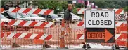  ?? MIKE CARDEW / BEACON JOURNAL ?? Kevin Afield of GoJo Industries walks past constructi­on project barriers on Exchange and Main streets in Akron on his way to lunch recently.