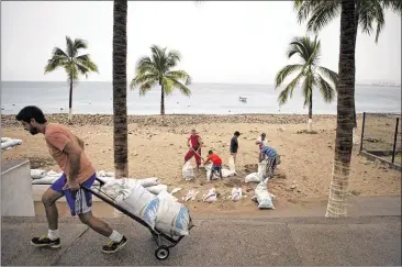  ?? REBECCA BLACKWELL / ASSOCIATED PRESS ?? Residents prepare for the arrival of Hurricane Patricia by filling sandbags to protect beachfront businesses in Puerto Vallarta, Mexico, on Friday. Forecaster­s called Patricia the strongest recorded storm ever in the Western Hemisphere. Locals and...