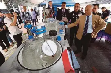  ??  ?? MOHMAD (kanan) menunjukka­n mesin memproses dadah yang dirampas dalam serbuan di Johor.