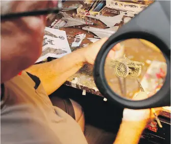  ?? ADRIAN LAM, TIMES COLONIST ?? Jack Funk, president of the Victoria Scale Modellers Club, holds a tiny cannon under a magnifying device. The club hosts its annual show on Saturday, with the First World War as a theme.