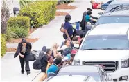  ?? MIKE STOCKER/SOUTH FLORIDA SUN-SENTINEL ?? People take cover outside the Fort Lauderdale-Hollywood Internatio­nal Airport after a shooter opened fire inside a terminal Friday in Fort Lauderdale, Fla.