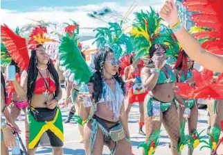  ?? JENNIFER LETT/SUN SENTINEL ?? Masquerade­rs dance during the Miami Carnival parade in Miami on Sunday.