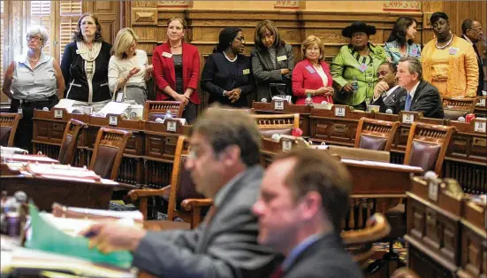  ?? JASON GETZ / FOR THE AJC 2012 ?? Several female members of the Georgia House of Representa­tives line up against the Senate Chamber walls to show their interest in the debate of House Bill 954, commonly referred as the “fetal pain” bill, during the 2012 General Assembly in the state Capitol.