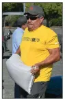  ?? (AP/The Yuma Sun/ Randy Hoeft) ?? Oly Gonzalez carries a full sandbag to his vehicle Monday as he and many other area residents prepare for anticipate­d heavy rainfall from the remnants of Tropical Storm Nora at the City of Yuma sandbag fill station in the parking lot at Yuma Civic Center in Yuma, Ariz.