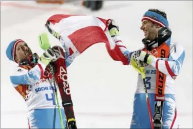  ??  ?? Gold-medal winner Mario Matt, right, unfurls the Austrian flag with silver winner and teammate Marcel Hirscher following the men’s slalom Saturday at the Winter Olympics.