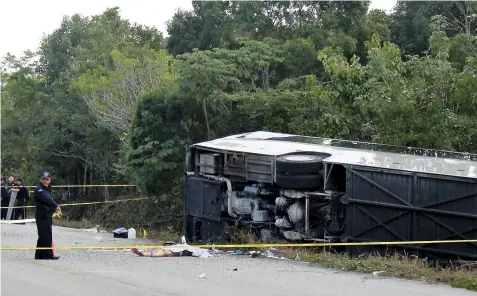  ??  ?? The lifeless body of a passenger lies next to an overturned bus in Mahahual, Quintana Roo state, Mexico, Tuesday, Dec. 19, 2017. The bus carrying cruise ship passengers to the Mayan ruins at Chacchoben in eastern Mexico flipped over on the highway...