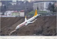  ?? Dogan News Agency / AFP / Getty Images ?? A Pegasus Airlines jetliner rests on an embankment after skidding off a runway in Trabzon, Turkey.