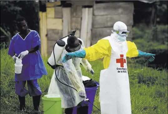  ?? Al-hadji Kudra Maliro The Associated Press ?? A health worker sprays disinfecta­nt on his colleague Sept. 9 after working at an Ebola treatment center in Beni, Congo.