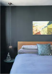  ??  ?? The dark walls and a statement Tom Dixon copper bronze pendant light give the main bedroom a touch of drama.