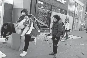  ?? SETH HARRISON/ USA TODAY NETWORK ?? People take merchandis­e from a Foot Locker store on 14th Street in Manhattan on June 1.