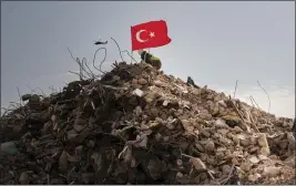  ?? EMILY GARTHWAITE — THE NEW YORK TIMES ?? A volunteer rescue worker plants a Turkish flag in the rubble of a collapsed building in Antakya, Turkey, on Saturday. The hard-hit area is struggling to keep residents safe.