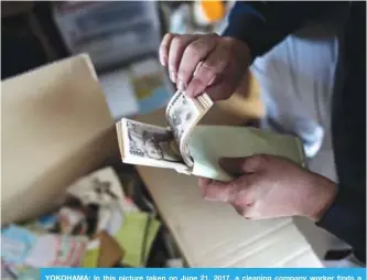  ?? —AFP ?? YOKOHAMA: In this picture taken on June 21, 2017, a cleaning company worker finds a stack of Japanese yen notes as he cleans up a woman’s apartment in Yokohama, who died alone in her apartment and was found days later.