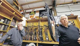  ?? ELAINE THOMPSON, THE ASSOCIATED PRESS ?? Sales clerk Tom Wallitner holds up a Mossberg 715T .22-calibre semi-automatic rifle during a 2017 auction at Johnny’s Auction House in Rochester, Washington.