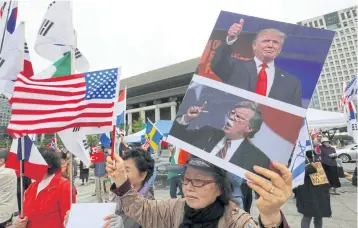  ?? AP ?? A protester in Seoul, South Korea holds portraits of US President Donald Trump, top, and National Security Adviser John Bolton.