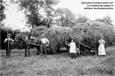  ??  ?? Agricultur­al workers pose next
to a loaded hay wagon in Hellidon, Northampto­nshire
