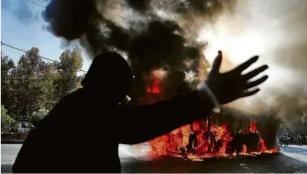  ?? Ivan Alvarado - 10.jan.20/Reuters ?? Manifestan­te em ato contra o governo chileno próximo a carro em chamas, em Santiago