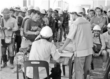  ??  ?? CIDB officers checking documents of constructi­on workers during the operation yesterday.
