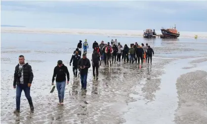  ?? ?? A group of migrants walk ashore in Dungeness, Kent, after crossing the Channel. Photograph: Gareth Fuller/PA