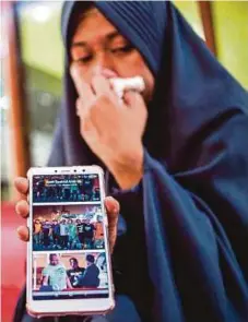  ?? AFP PIC ?? Syachrul Anto’s wife, Lyan Kurniawati, showing her husband’s photograph­s after the funeral in Surabaya yesterday.