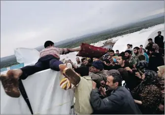  ?? MUHAMMED MUHEISEN/ THE ASSOCIATED PRESS ?? Syrians who fled their homes struggle to get pillows and blankets this week at a camp for the displaced in the village of Atmeh, Syria. This tent camp has about 12,000 people, including 3,000 children.