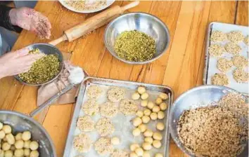  ??  ?? Top and above: Christmas cookies being baked at Newcomer Kitchen, in Toronto. Left: Esmail Al Salha hands out samples of his homemade sweets to customers at Crown Pastries, the first Syrian food business to make its mark in Toronto. Top right:...