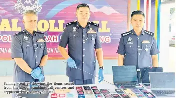  ?? ?? Sammy (centre) showing the items seized from the illegal gambling call centres and cryptocurr­ency scam syndicate.