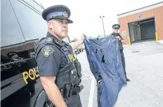  ?? BOB TYMCZYSZYN/STANDARD STAFF ?? Acting Staff Sgt. Daniel Briggs and Sgt. David Brazier hold up a damaged air mattress. The OPP are appealing for witnesses in relation to a fatal crash July 7 on Highway 406 in Welland. A motorcycli­st was killed when he struck the inflated mattress and...