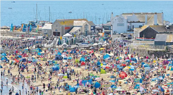  ??  ?? Families make the most of the half-term hot weather at Lyme Regis in Dorset. The heatwave is expected to be followed by rain at the weekend, while there may be torrential downpours today in the South East