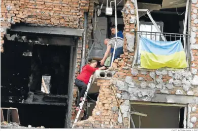  ?? OLEG PETRASYUK / EFE ?? Varias personas tratan de acceder a una vivienda destruida en Irpin, en la región de Kiev.