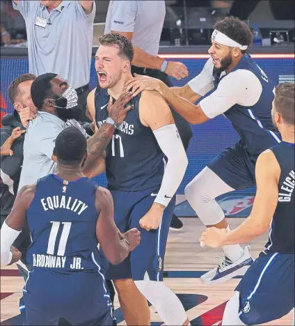  ?? FOTO: AP ?? Doncic agasajado por sus compañeros, instantes después de haber logrado el triple que dio la victoria a los Dallas Mavericks