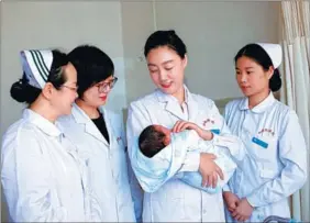  ?? PHOTOS PROVIDED TO CHINA DAILY ?? Ding Guifeng, head of Urumqi Youai Hospital, holds a newborn.