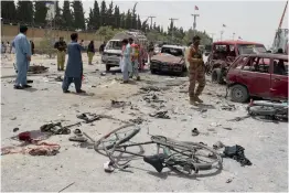  ?? — AFP, AP ?? Pakistani security personnel gather at the site of a suicide attack near a polling station in Quetta on Wednesday. ( Right) A Pakistani woman mourns the death of her family member outside a hospital in Quetta.