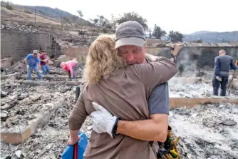  ?? THE ASSOCIATED PRESS ?? Standing where his home used to be, Craig Bolleson hugs a friend Monday in the SunlandTuj­unga section of Los Angeles.