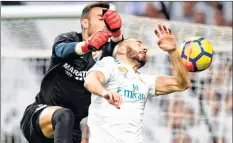  ??  ?? Real Madrid's Karim Benzema (R) and Malaga's goalkeeper Roberto jump for the ball during their Spanish league match on Saturday in Madrid. Real Madrid won the match 3-2. Karim, Casemiro and Christiano Ronaldo scored a goal apiece for the winners.