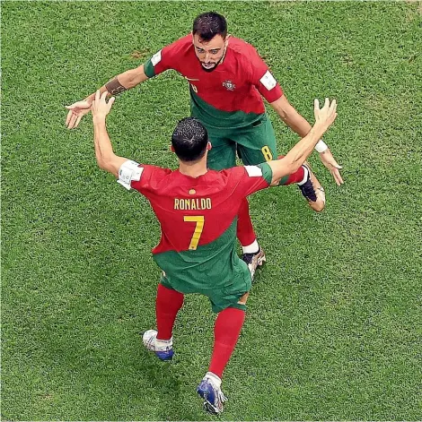  ?? GETTY IMAGES ?? RCaopntail­odno1 was again the centre of attention but for a goal he didn’t score for Portugal in their win over Uruguay. The goal was credited to Bruno Fernandes, who celebrates with Ronaldo. Fernandes scored Portugal’s second from the penalty spot late in the match.