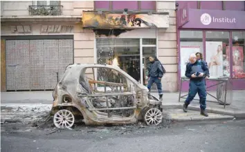  ?? — AFP ?? Police look at a burnt car in Beaubourg street in Paris on Sunday a day after a ‘yellow vest’ demonstrat­ion.