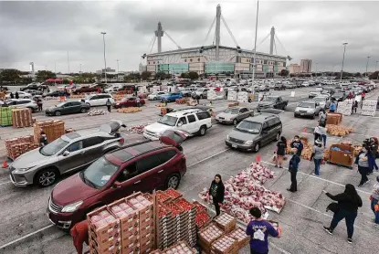  ?? Photos by Billy Calzada / Staff photograph­er ?? San Antonio Food Bank volunteers work to load food into vehicles for more than 2,000 families at the Alamodome on Tuesday morning. Eric Cooper, Food Bank president and CEO, said he is “grateful to our city for hearing the call.”