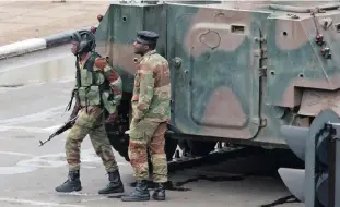  ??  ?? Armed soldiers stand by an armoured vehicle on the road leading to President Robert Mugabe’s office in Harare, Zimbabwe, this week.