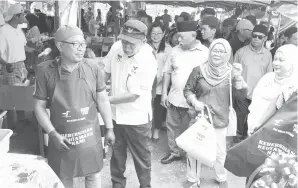  ?? ?? UTAMAKAN KEBERSIHAN: Len memasang apron kepada seorang peniaga di Bazar Ramadan Sarikei kelmarin.