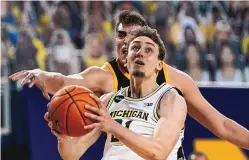  ?? CARLOS OSORIO/ASSOCIATED PRESS ?? Michigan guard Franz Wagner goes up for a layup in the Wolverines’ Big Ten rout of Iowa on Thursday night. Defending at rear is star Hawkeye center Luka Garza.