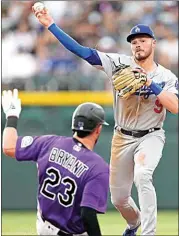  ?? DAVID ZALUBOWSKI / AP ?? Los Angeles Dodgers second baseman Gavin Lux, right, throws over Colorado Rockies’ Kris Bryant (23) after forcing Bryant out at second on the front end of a double play hit into by Brendan Rodgers during the third inning of a baseball game on Monday in Denver.