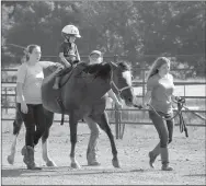  ?? Janelle Jessen/Herald-Leader ?? Zander Thompson (second from left) receives speech therapy from Holly Meyers (second from right) as sidewalker Sarah Ragsdale (left) and horse-handler LeTausha Ahrents (right) help with the therapy session.