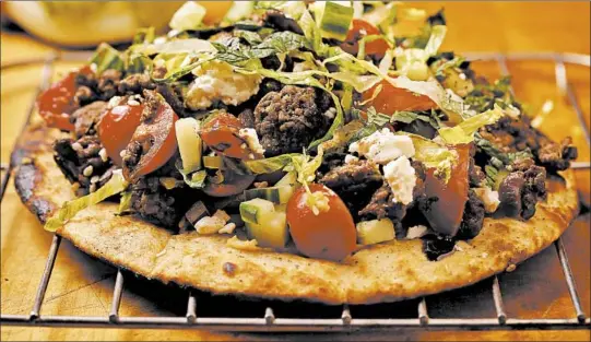  ?? E. JASON WAMBSGANS/CHICAGO TRIBUNE; SHANNON KINSELLA/FOOD STYLING ?? Try using pita bread as a base for an open-faced sandwich, with toppings like tomatoes, onion feta cheese and ground lamb.