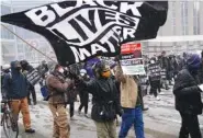  ?? AP PHOTO/JIM MONE ?? A group of protesters march in the snow around the Hennepin County Government Center on Monday in Minneapoli­s where the second week of jury selection continues in the trial for former Minneapoli­s police officer Derek Chauvin.