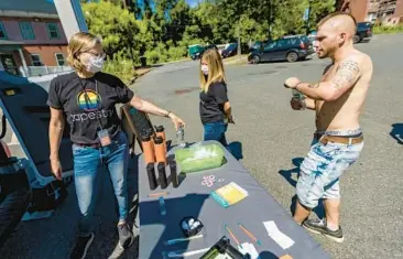  ?? JESSE COSTA/WBUR/KAISER HEALTH NEWS ?? Tapestry Health Systems nurse Katy Robbins hands a bottle of water to Kyle as he visits the harm reduction mobile unit in Greenfield, Mass. An animal tranquiliz­er is appearing in the fentanyl supply.