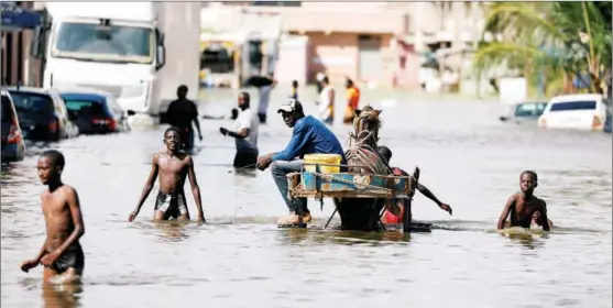  ?? ZOHRA BENSEMRA / REUTERS ?? Residents walk through a flooded street after heavy rains in Keur Massar, Senegal, on Sept 8.